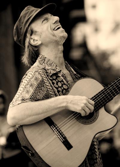 Henrique Lissovsky sorrindo e tocando violão